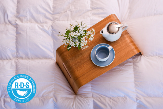 A tray with a cup of tea and flowers, accompanied by a Hungarian Goose Down duvet.